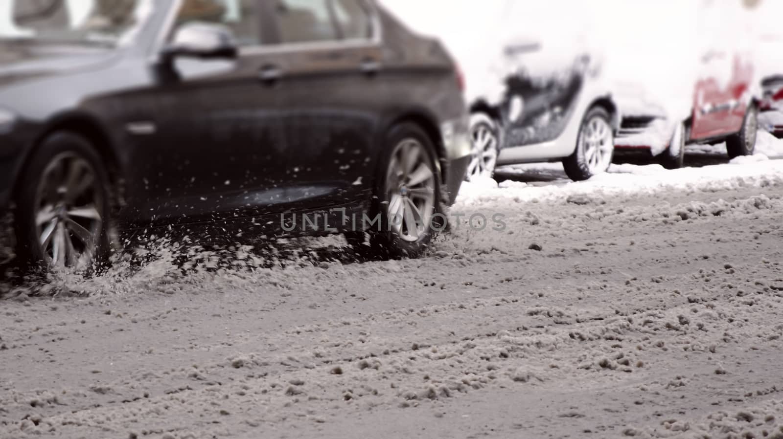 a car passing on the city road covered with melted and dirty snow by rarrarorro