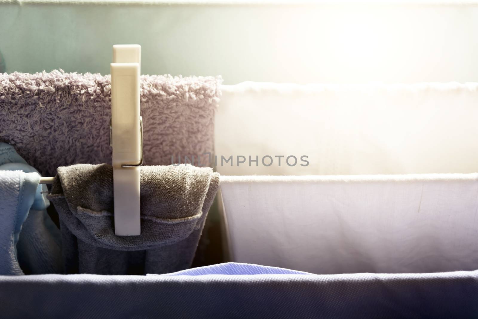 a white clothespin holds a dress hanging on a drying rack to dry. Sunlight beam coming from the window. Household chores and laundry