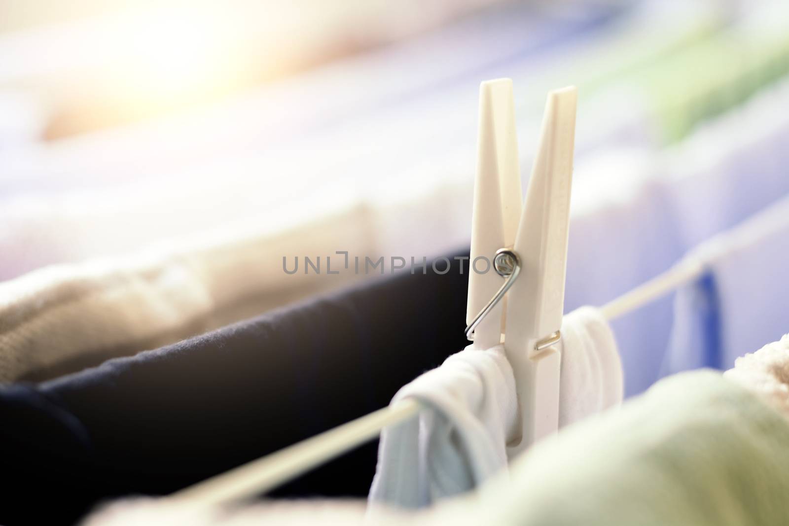 a white clothespin holds a dress hanging on a drying rack to dry. Sunlight beam coming from the window. Household chores and laundry