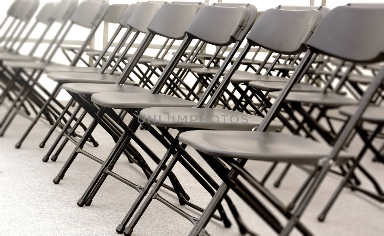 a group of black folding chairs arranged in a row for a convention