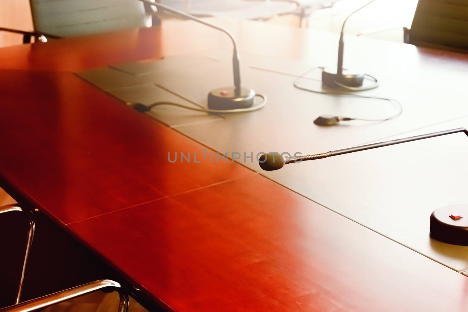 tabletop microphone on a wooden table in a boardroom. Natural light coming in through the window. Meetings and conferences