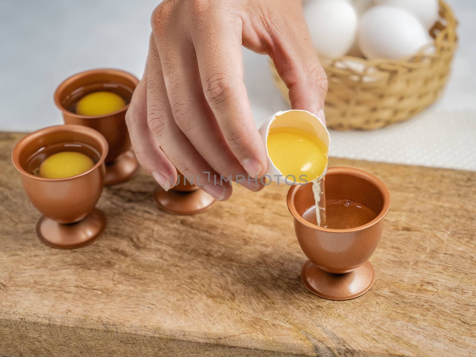 A hand pouring an egg into a copper egg cup.