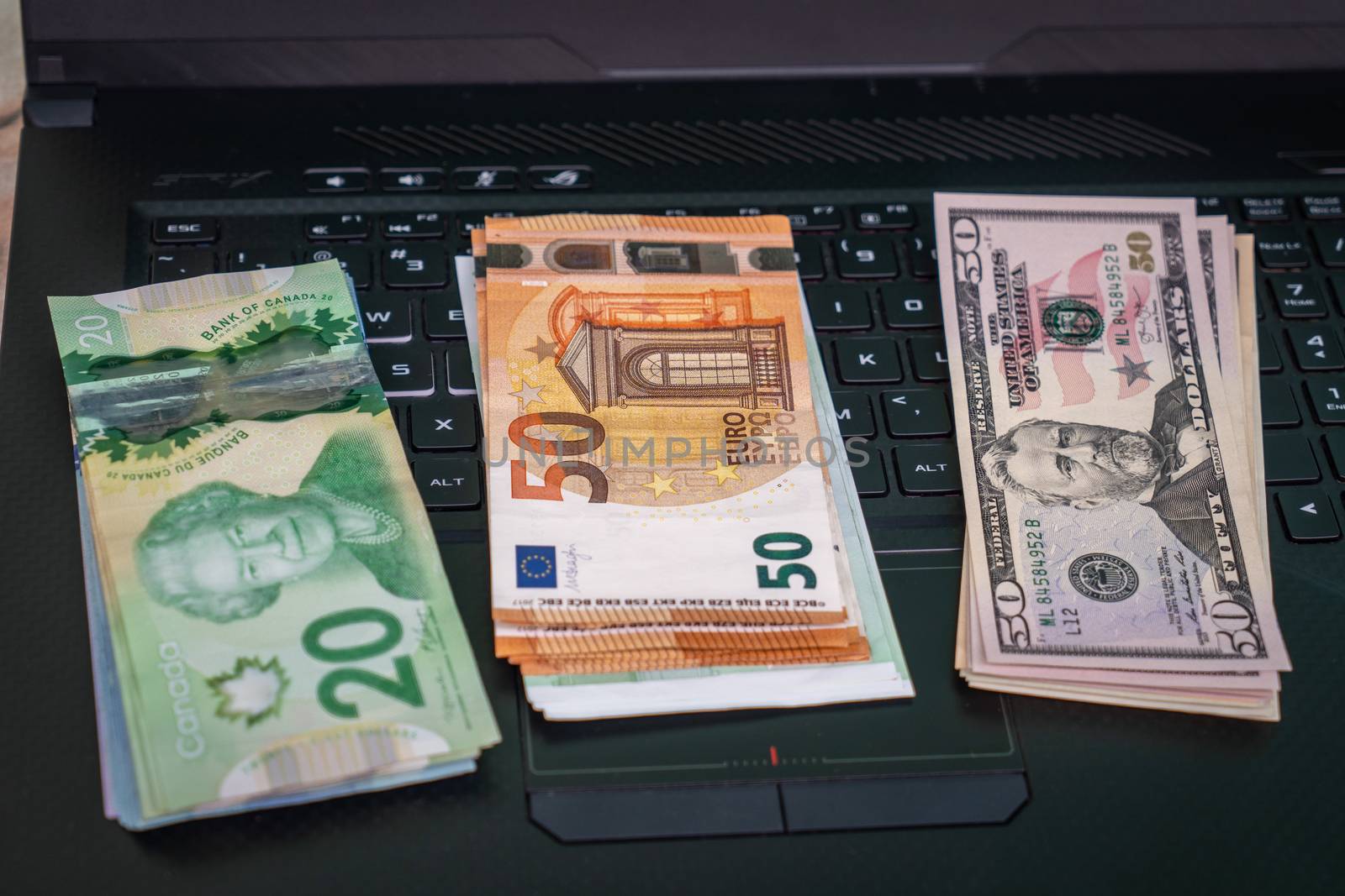 Three groups of banknotes, one of canadian dollars, other of euros and the other of American dollars
