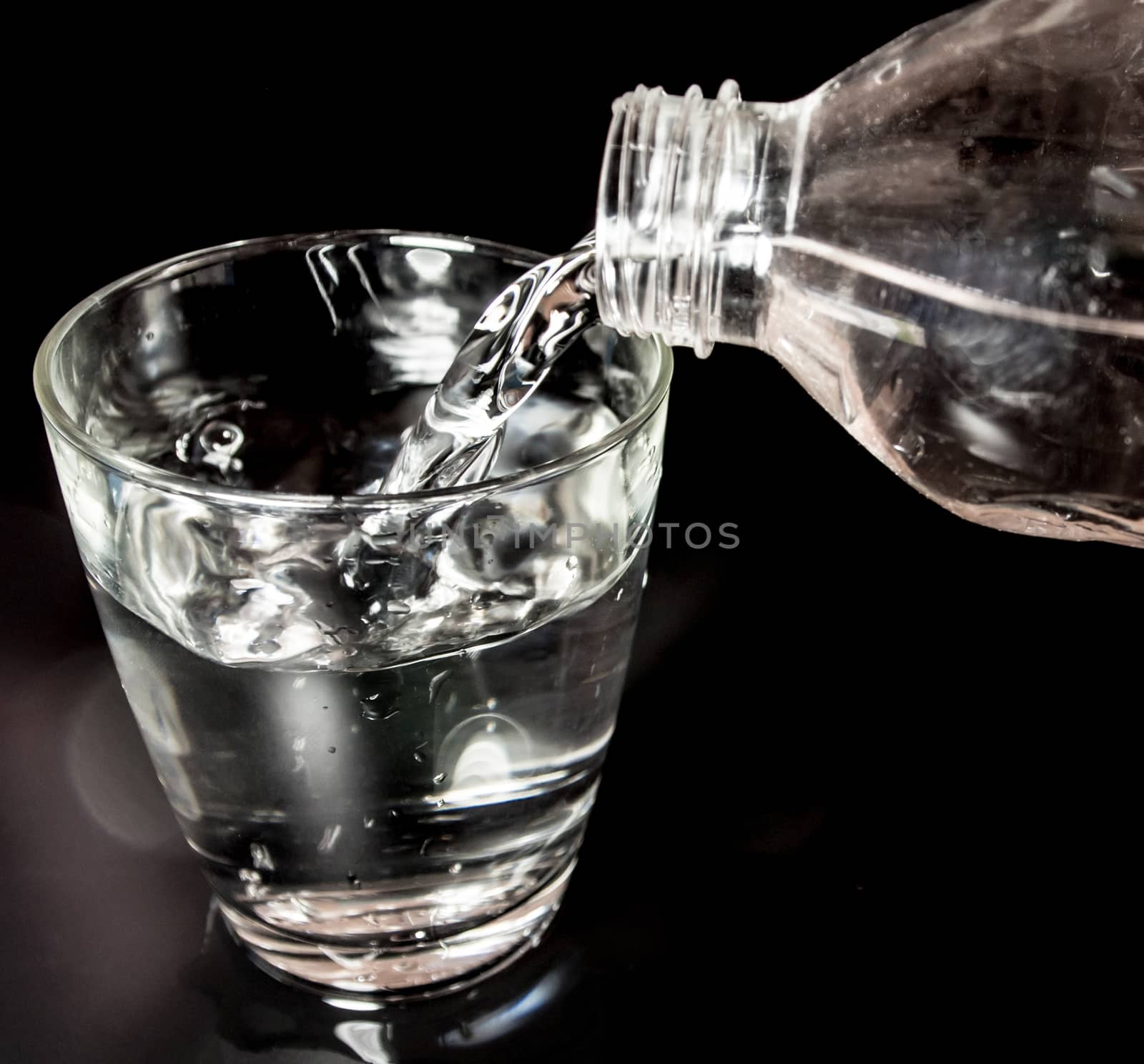 Pour water from the bottle into the glass by Satakorn