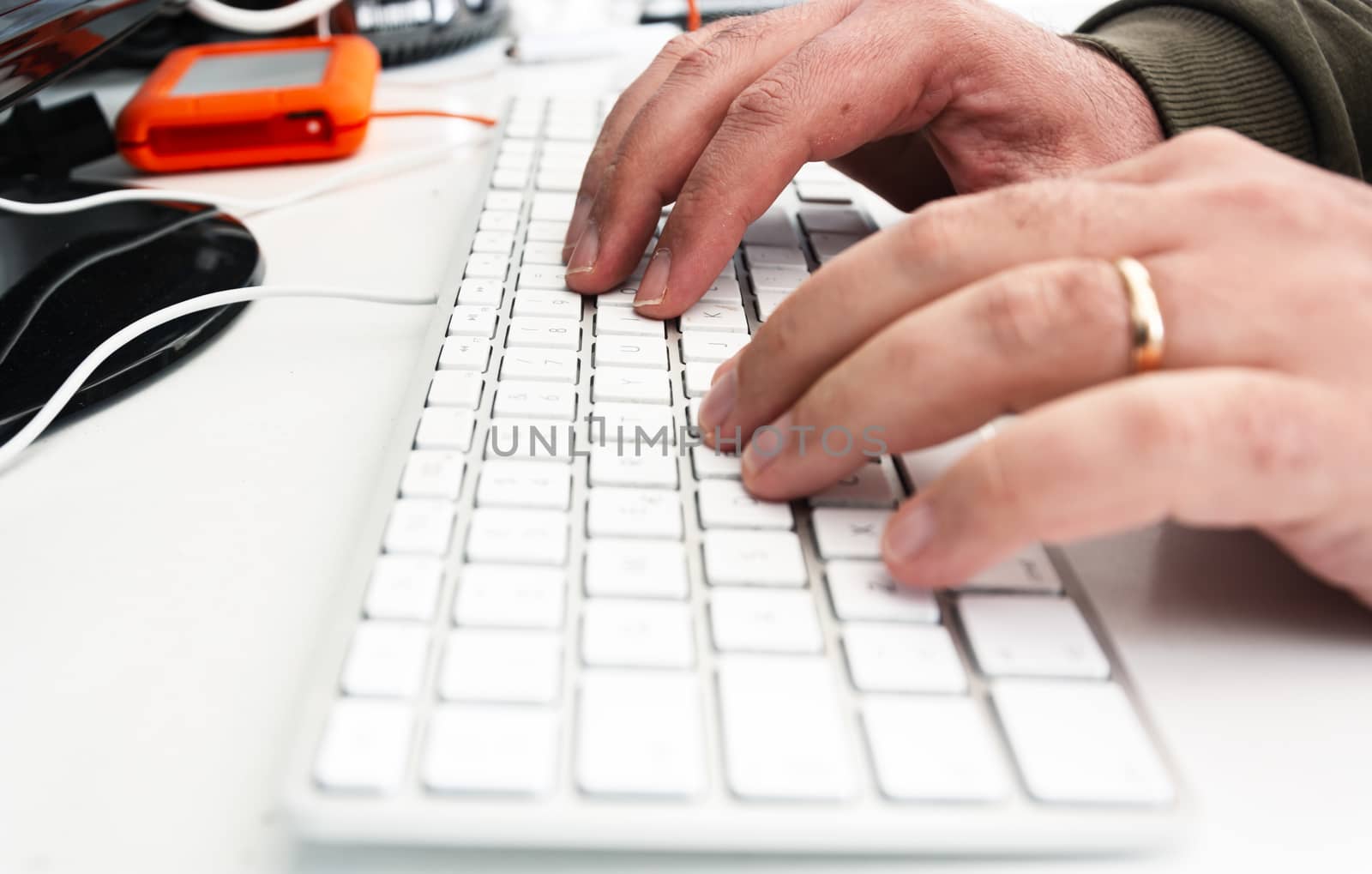 male hands typing keys on a white computer keyboard in an office. by rarrarorro