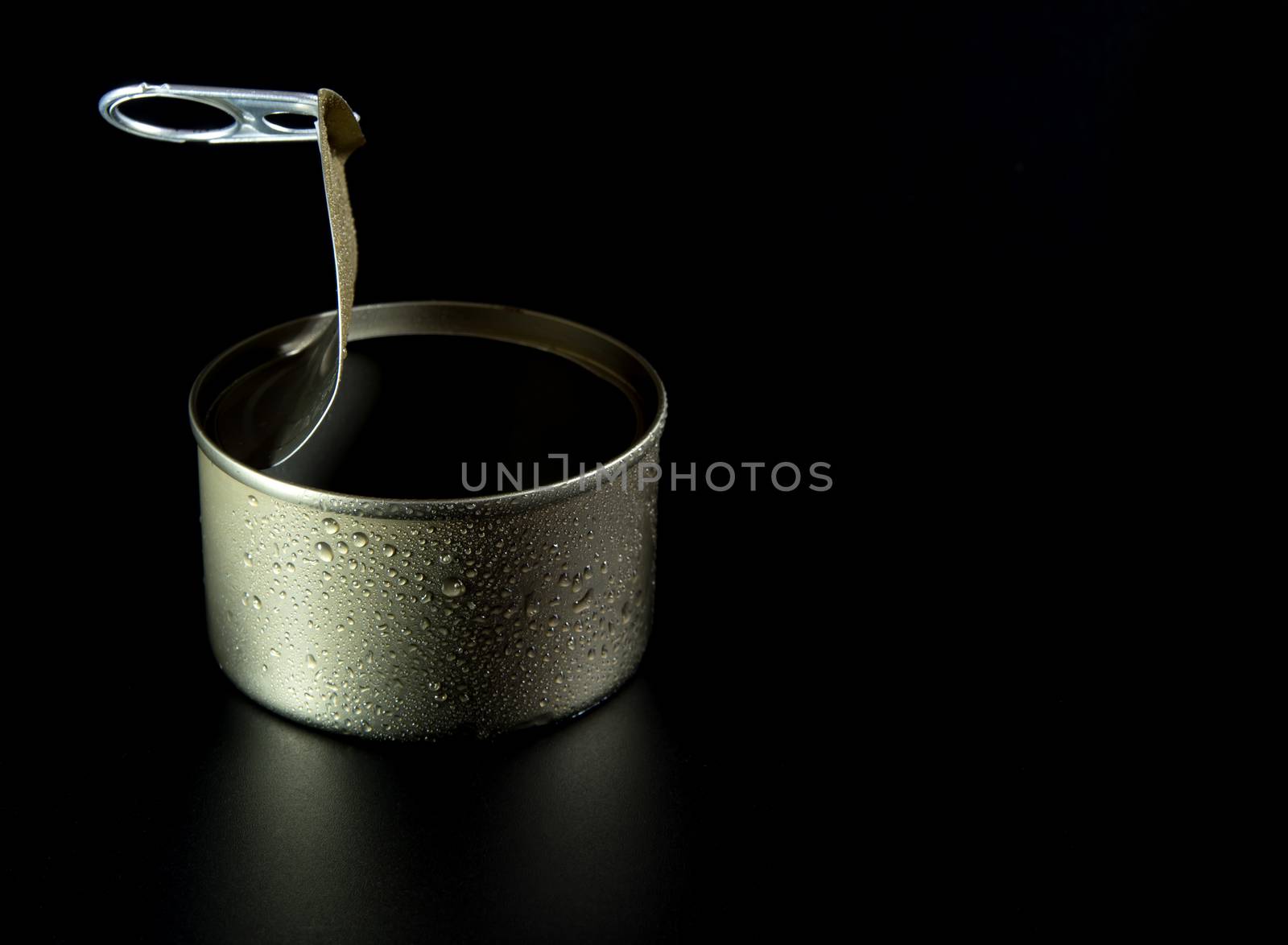 Opened pull cap of empty food can on black background