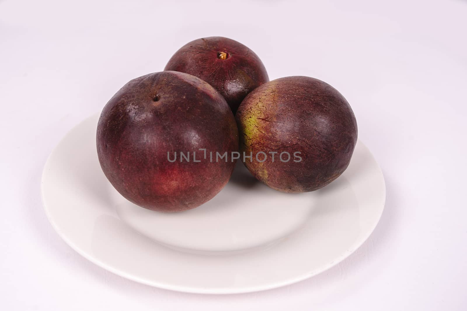 Three caimito fruits on a plate