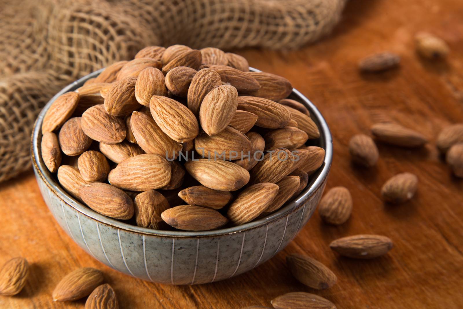 Almonds in bowl on wooden background