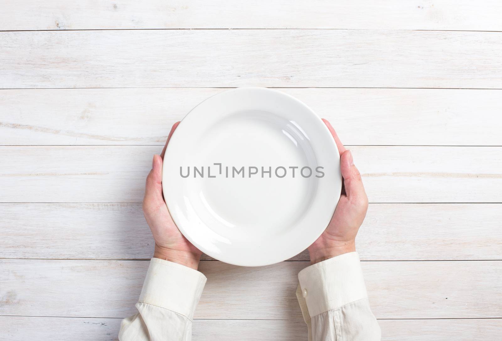 Business lunch and healthy food theme: man's hand holding a white empty plate