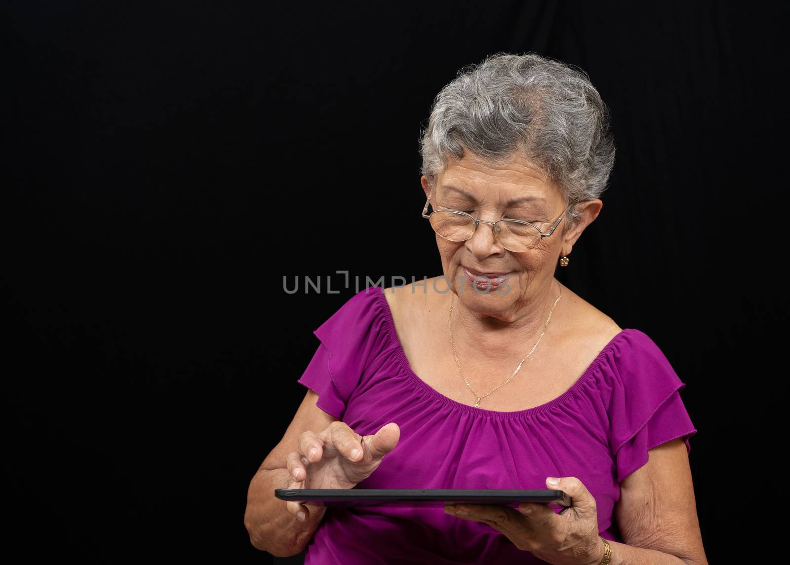 Elder woman wearing glasses with a tablet