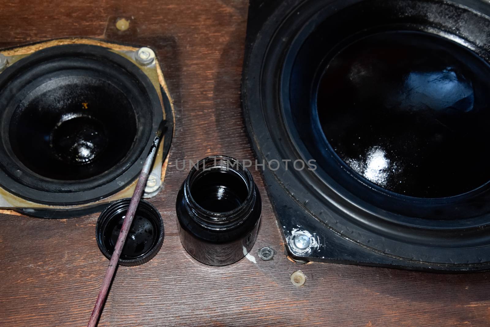 Painting the diffusers of speakers with stamp paint to give them aesthetics. Ink and brush next to the speakers.