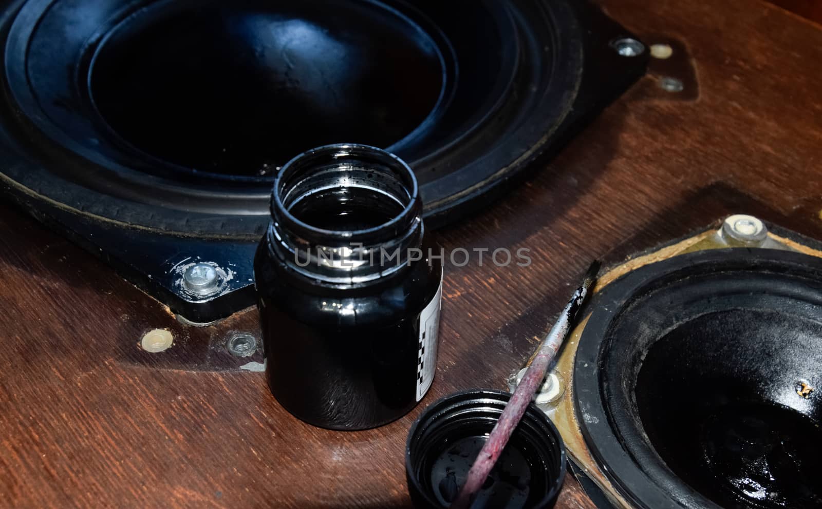 Painting the diffusers of speakers with stamp paint to give them aesthetics. Ink and brush next to the speakers.