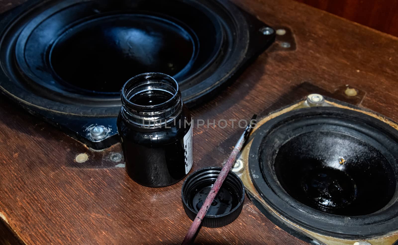 Painting the diffusers of speakers with stamp paint to give them aesthetics. Ink and brush next to the speakers.