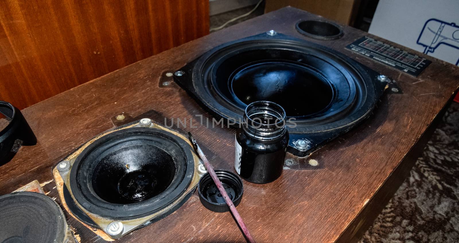 Painting the diffusers of speakers with stamp paint to give them aesthetics. Ink and brush next to the speakers.