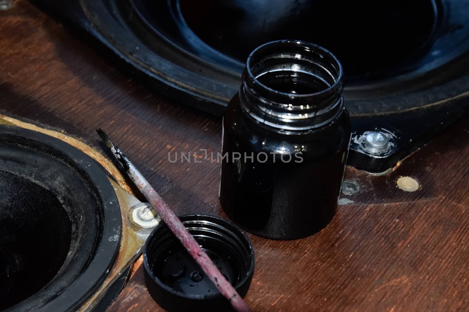 Painting the diffusers of speakers with stamp paint to give them aesthetics. Ink and brush next to the speakers.