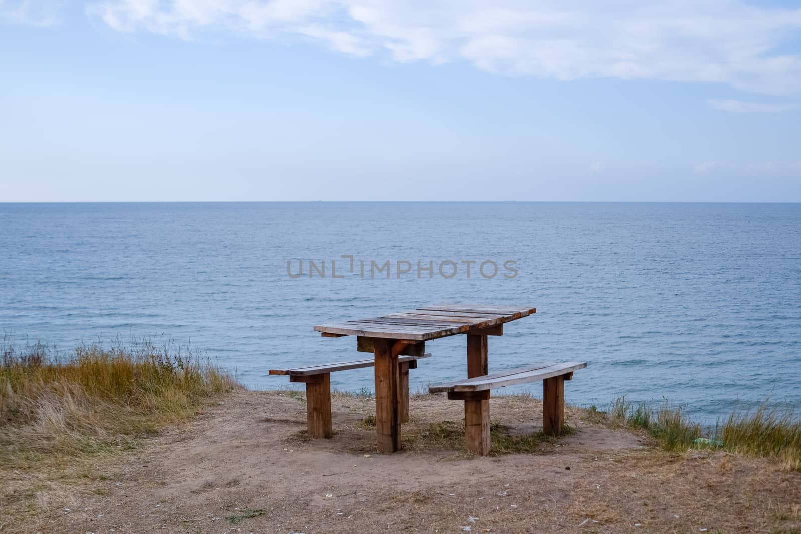 A table and benches by the sea. A place to sit and relax.