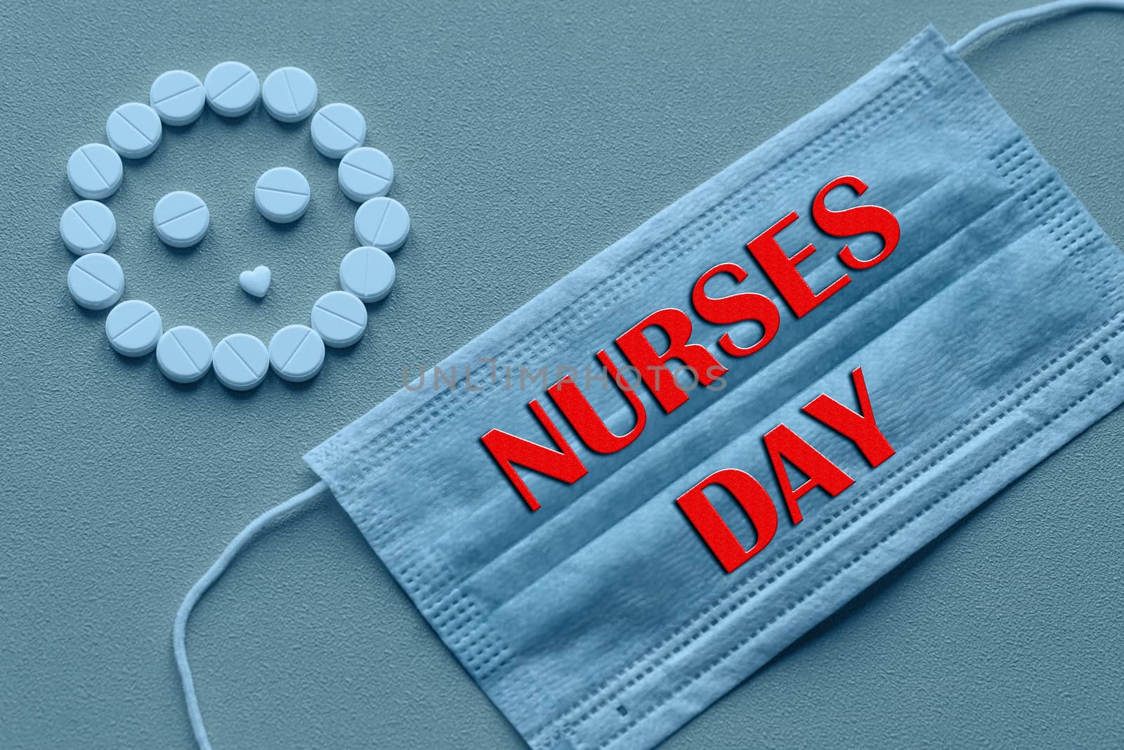 White tablets are arranged in the form of a smiley face on a yellow background. Text of congratulations on the medical holiday nurse's Day by bonilook