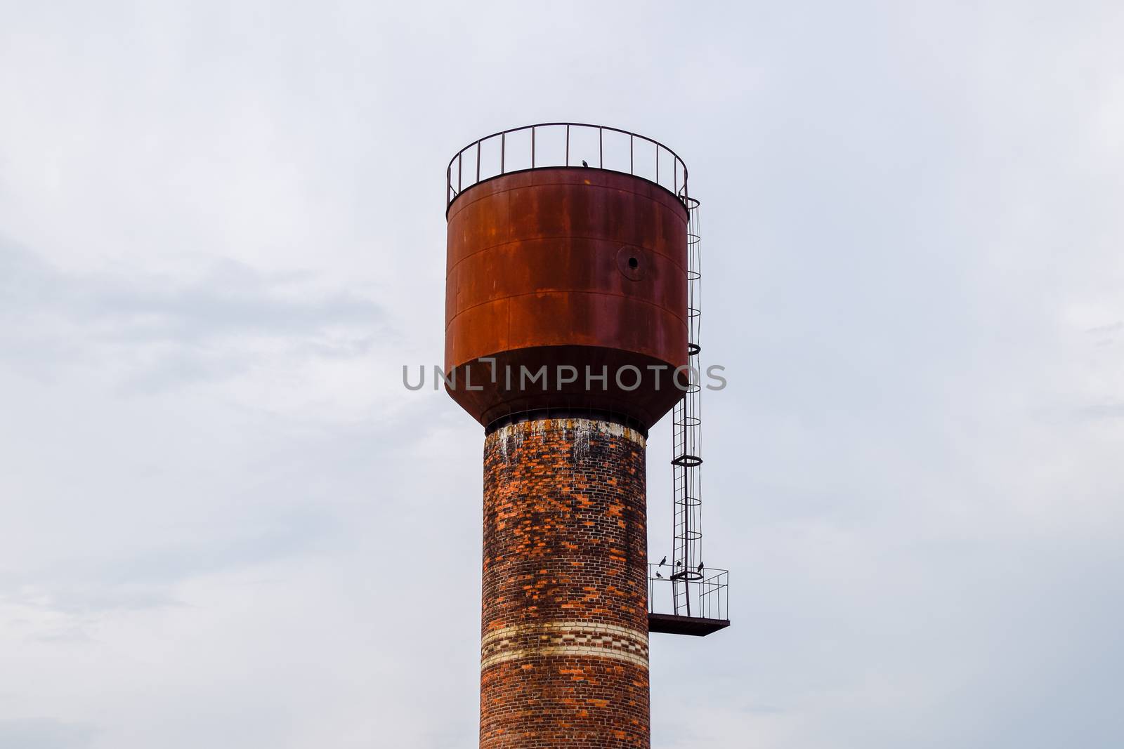 Rusty water tower against sky. Old water pump. by fedoseevaolga