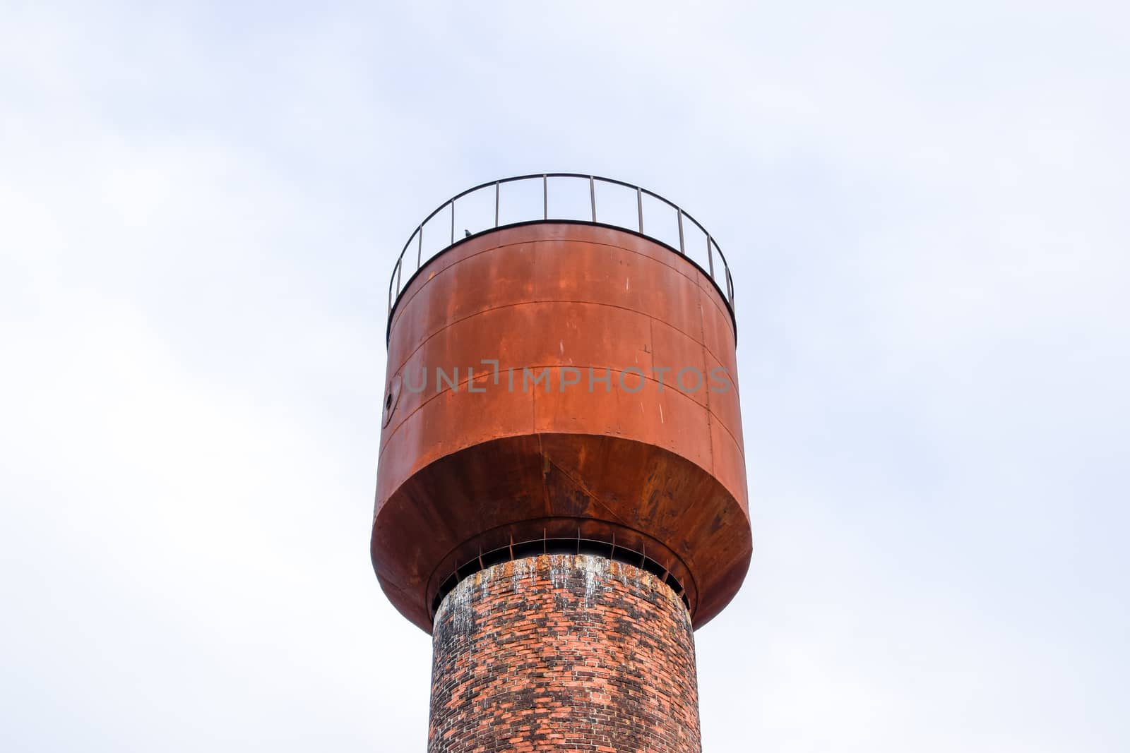 Rusty water tower against the sky. Old water pump.