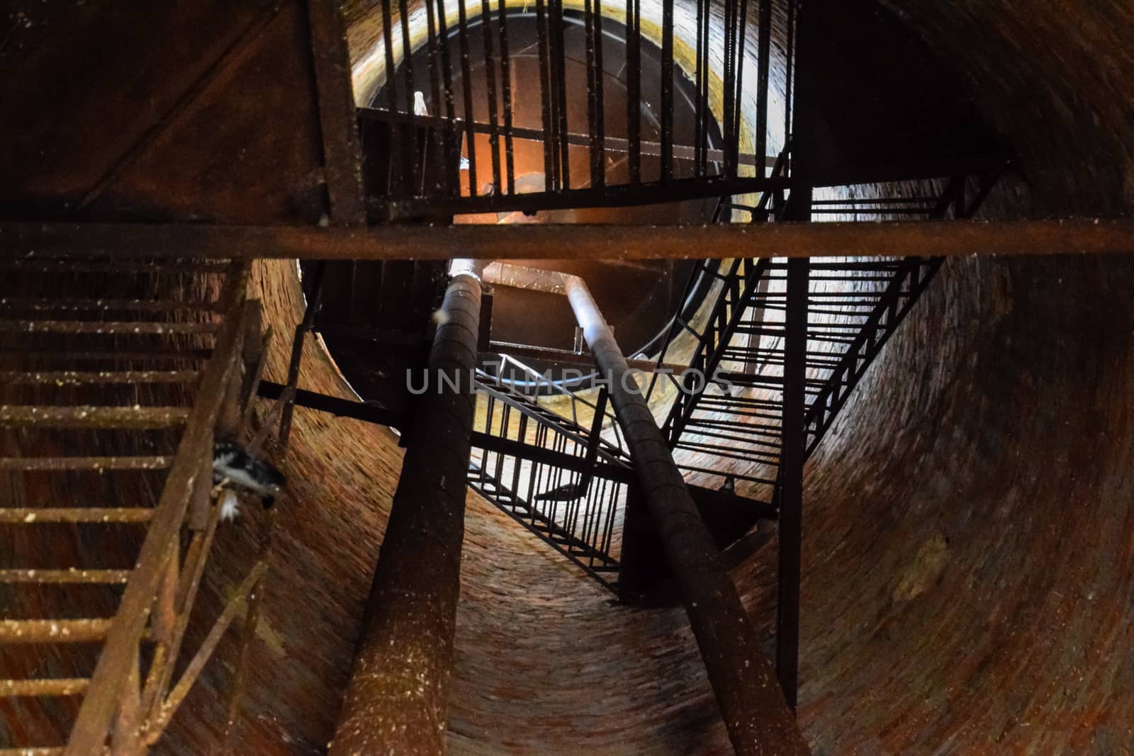 Rusty water tower inside view from top to bottom. Old water pump. Ladder to the water tank, pigeon droppings.