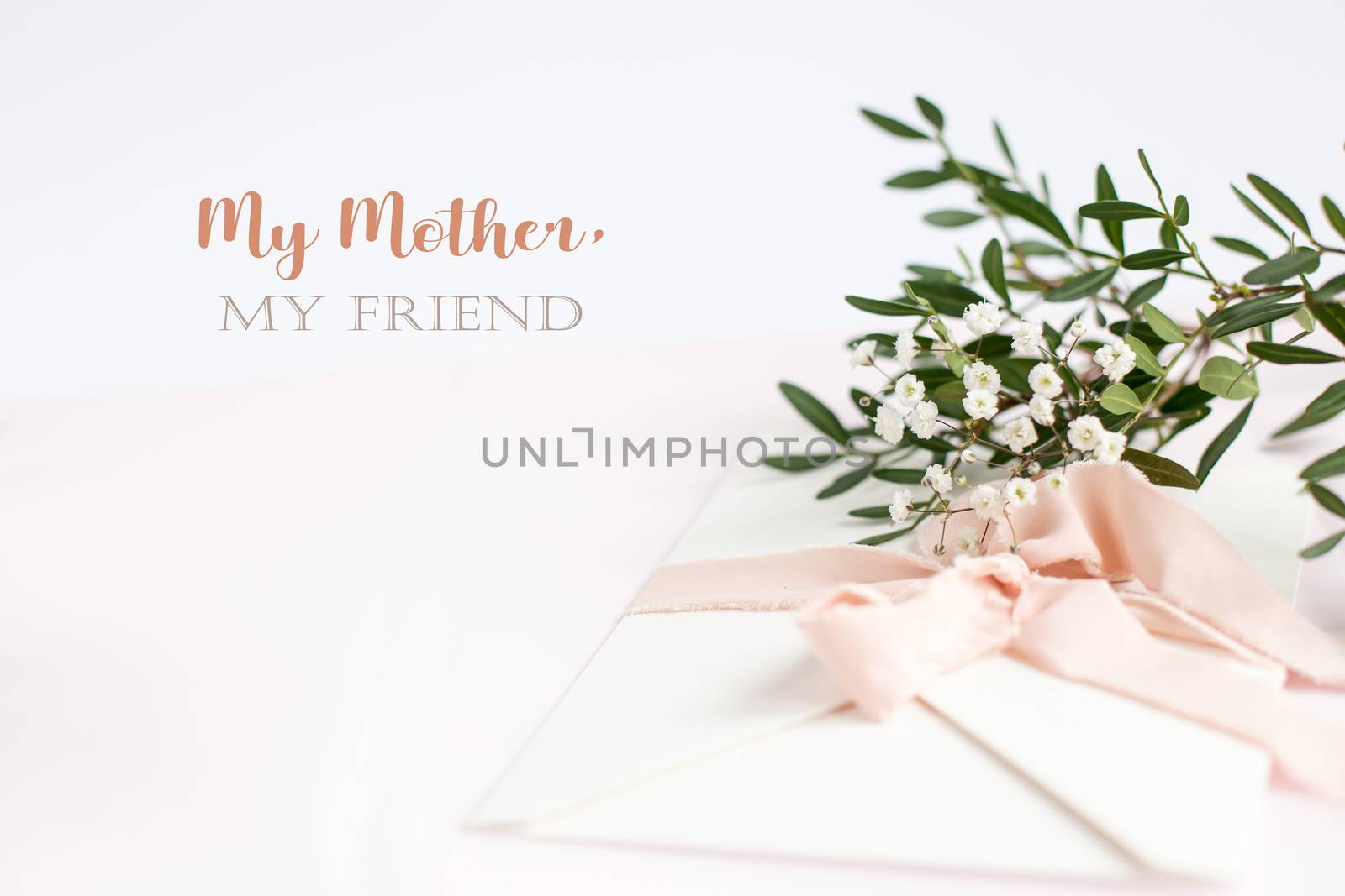 Envelope on a white-pink background with peach silk ribbon, green branch and flowers. Mother's day card.