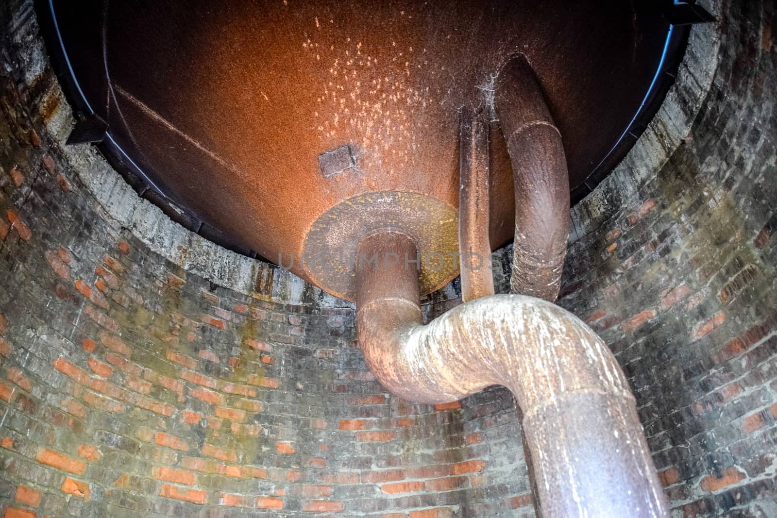 Water tank of an old water tower. Rusty tank and pipes of the water system.