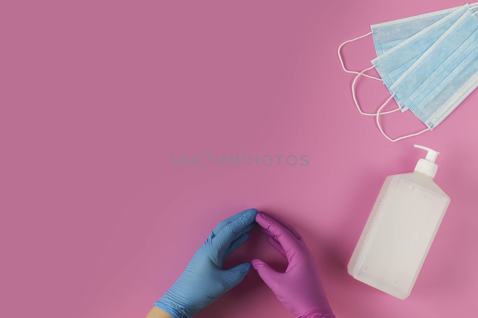 Protective medical white face mask and sanitizer gel on a pink background, success with a heart symbol made by a doctor's hands.  View from above. Virus Prevention Space for text. Close up, gorizontal orientation