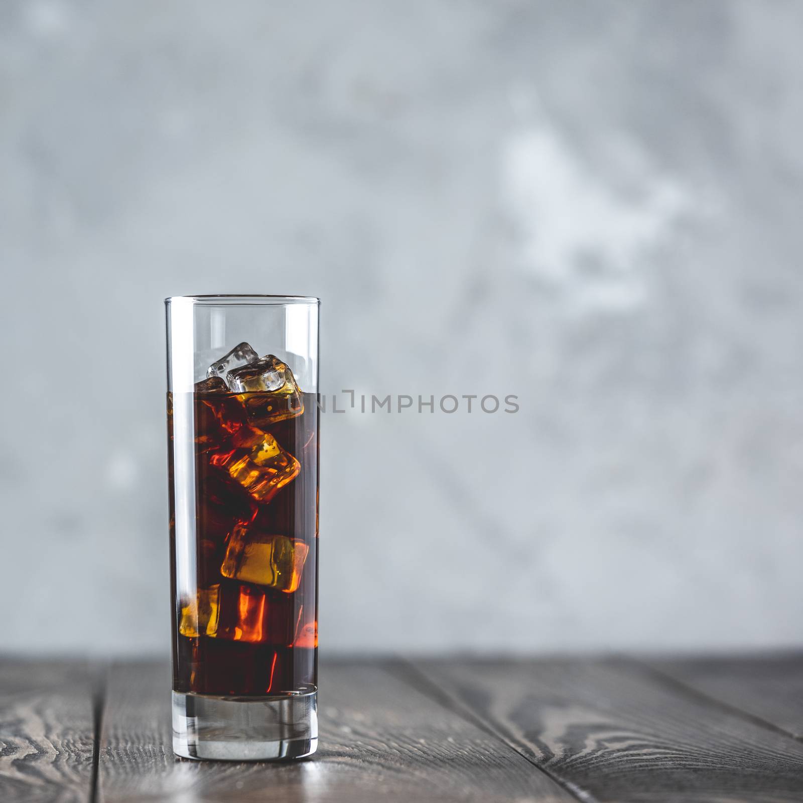 Glass of brew cold coffee and ice. Cold summer drink on a dark wooden table and gray background with copy space.