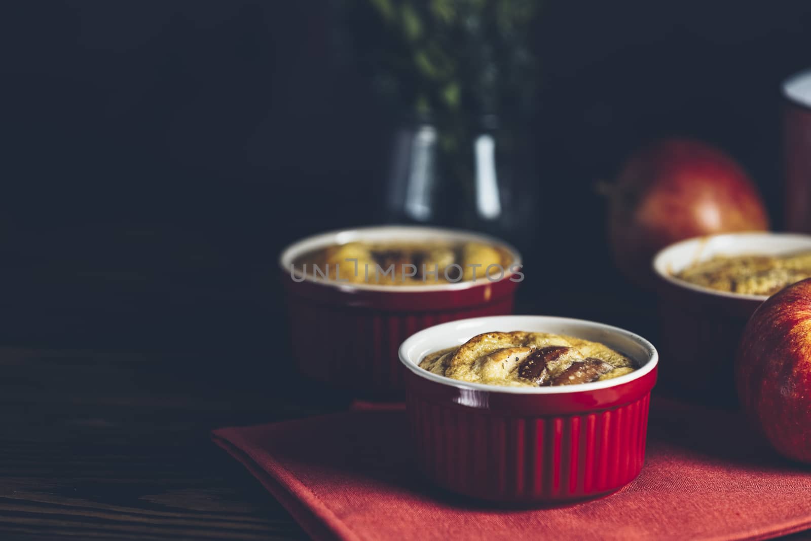 Apple pie in ceramic baking molds ramekin on dark wooden table. Close up, shallow depth of the field. Romantic breakfast or supper with coffee.