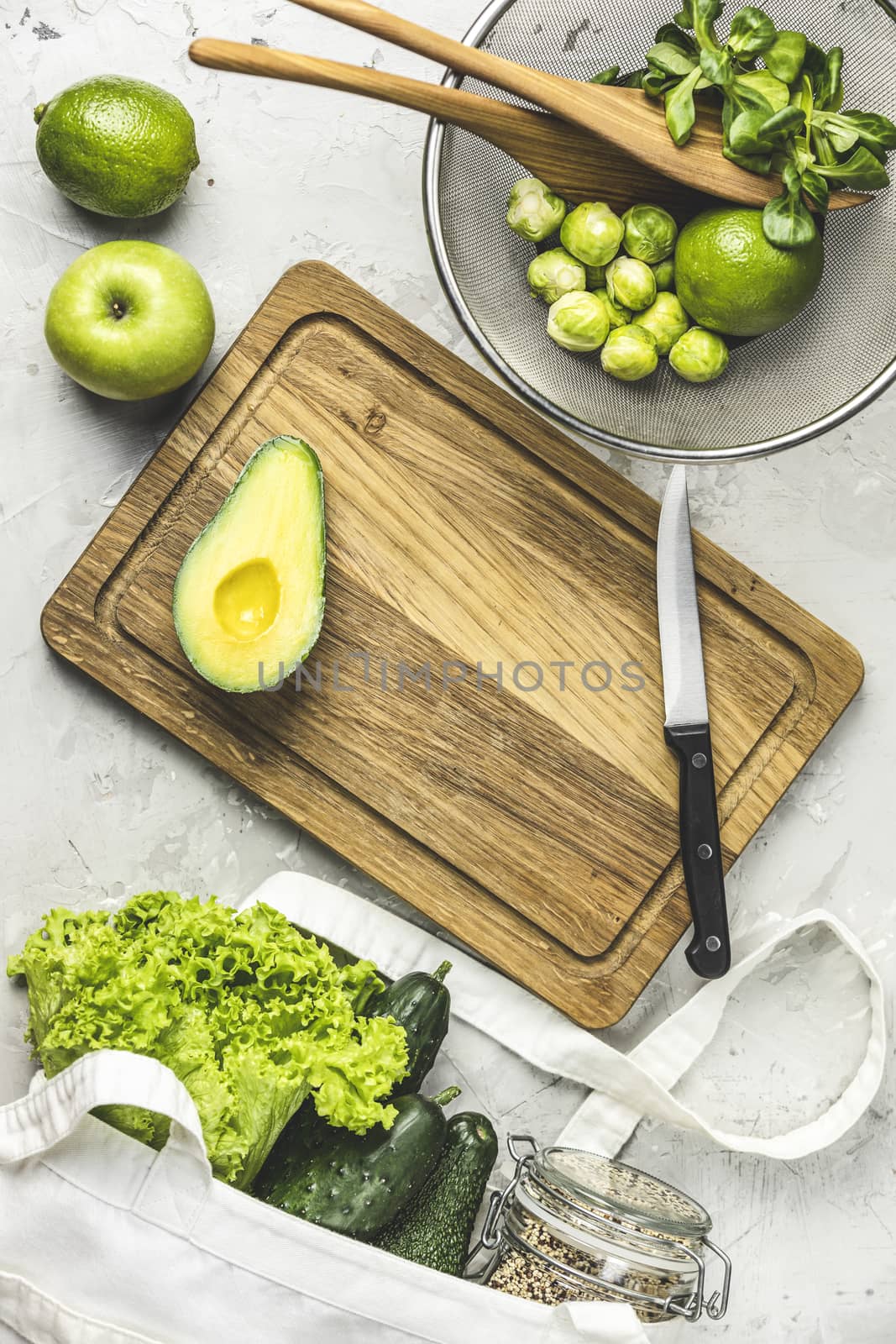 Fresh organic ingredients for salad making on green background. Spring diet, healthy raw vegetarian, vegan concept, detox breakfast, alkaline clean eating. Copy space.