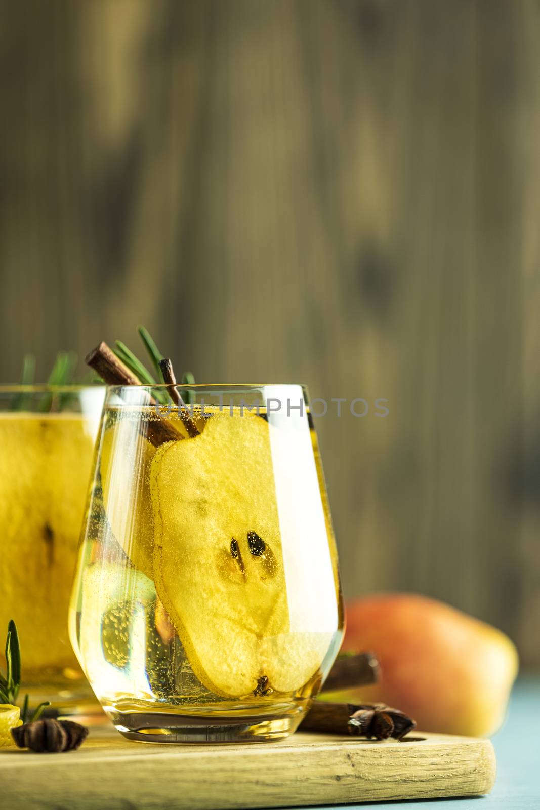 Festive summer drinks, pear spice cocktail. Hot drink cocktail for Christmas, winter or autumn holidays. Served with ingredients on light blue surface.