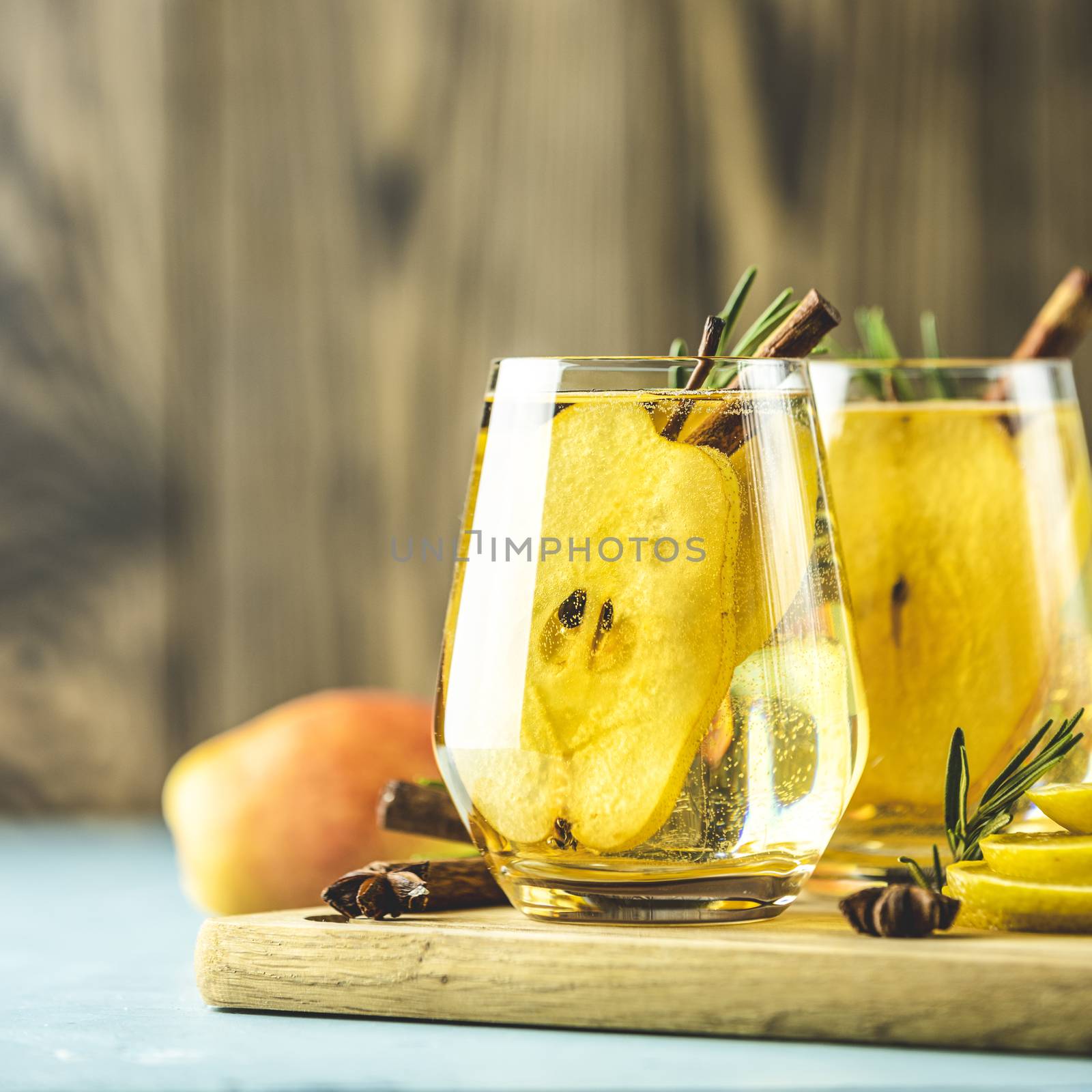 Festive summer drinks, pear spice cocktail. Hot drink cocktail for Christmas, winter or autumn holidays. Served with ingredients on light blue surface.