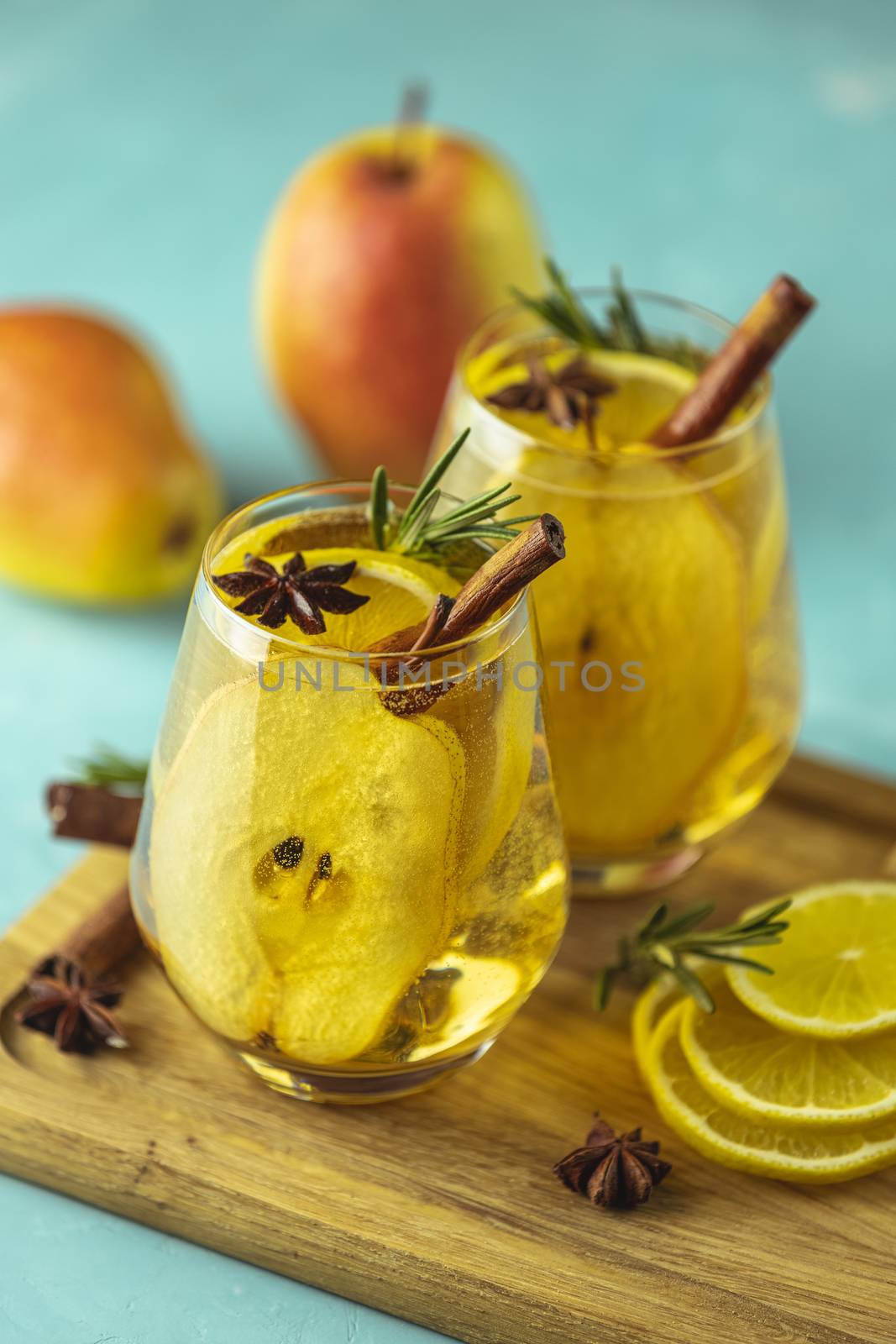 Festive summer drinks, pear spice cocktail. Hot drink cocktail for Christmas, winter or autumn holidays. Served with ingredients on light blue surface.