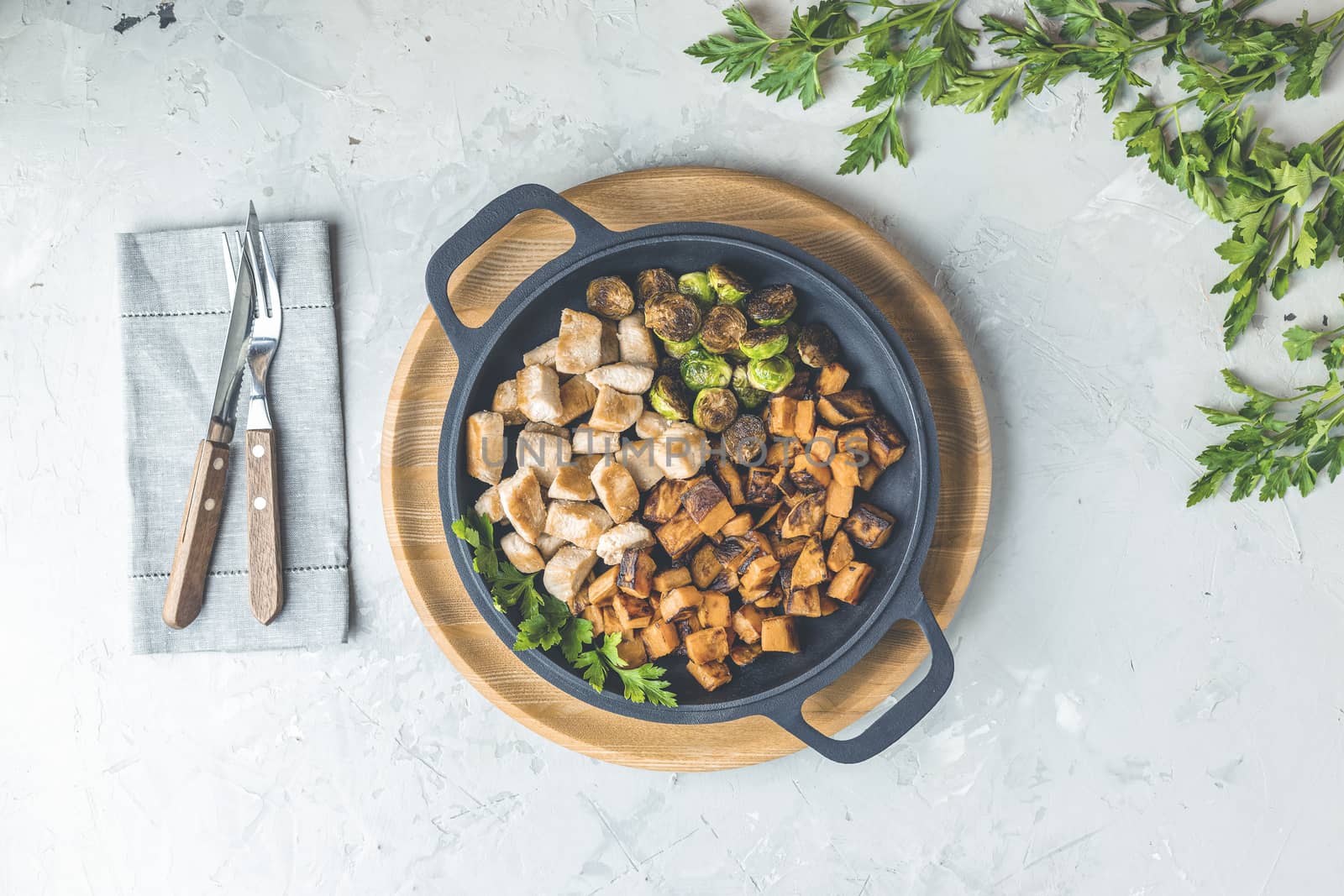 Healthy food. Pan of baking chicken meat, fried sweet potato and brussels sprouts. Top view, light gray concrete surface, flat lay.	