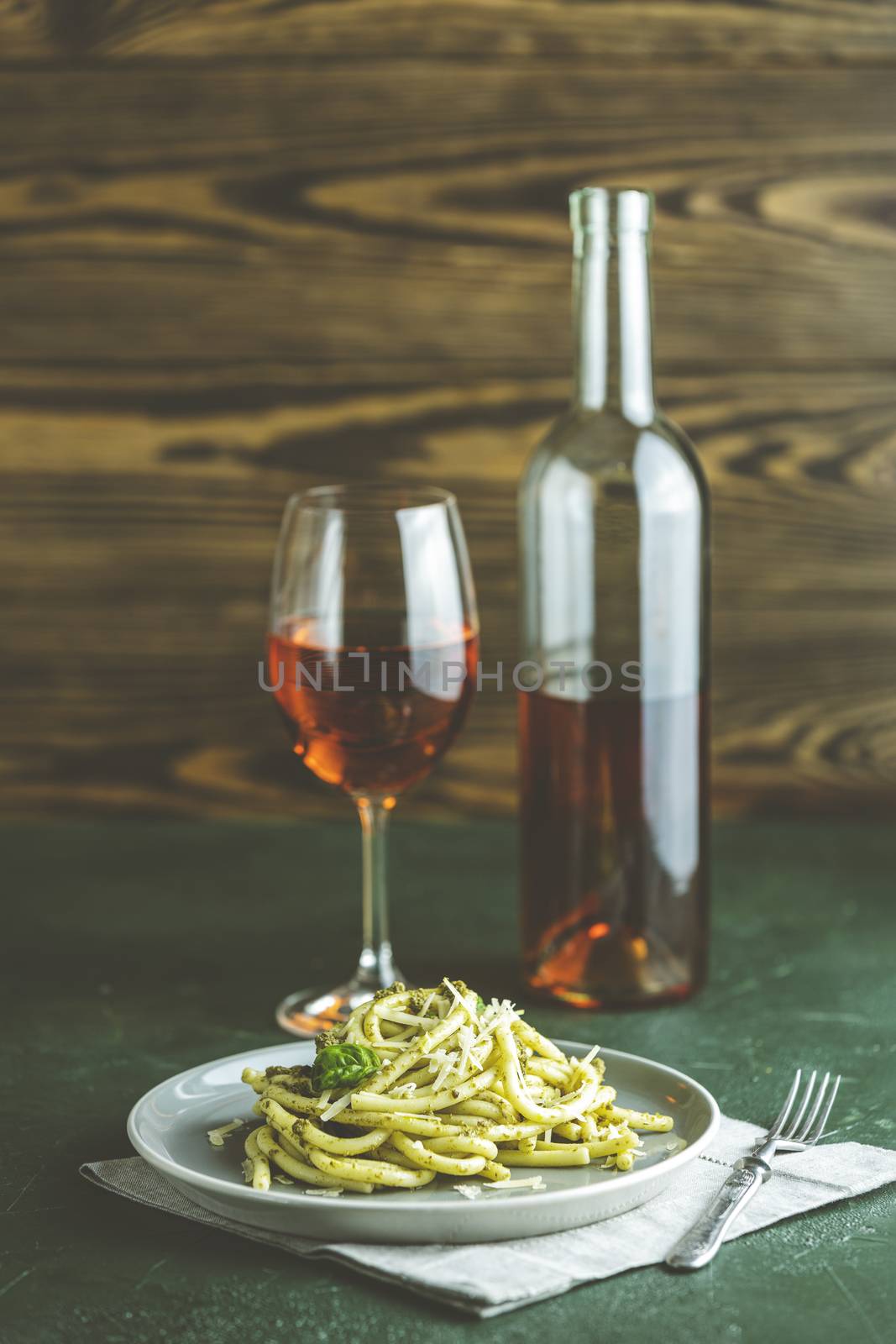 Spaghetti pasta bucatini with pesto sauce and parmesan. Italian traditional perciatelli pasta by genovese pesto sauce in gray dish served with wine	