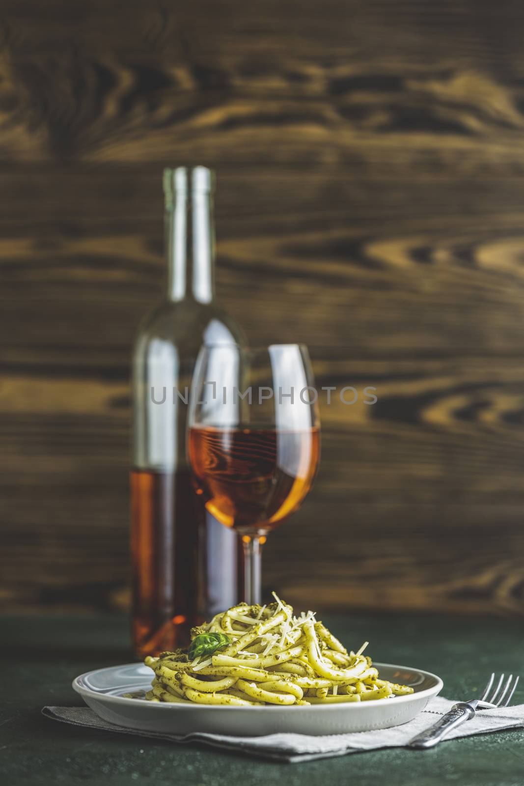 Spaghetti pasta bucatini with pesto sauce and parmesan. Italian traditional perciatelli pasta by genovese pesto sauce in gray dish served with wine