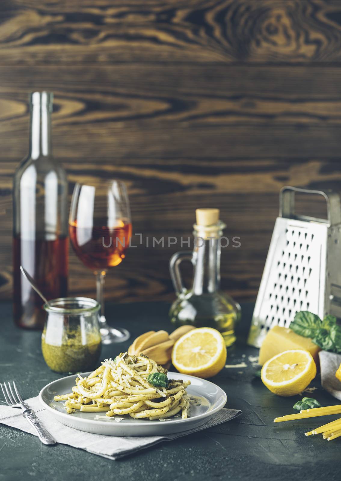 Spaghetti pasta bucatini with pesto sauce and parmesan. Italian traditional perciatelli pasta by genovese pesto sauce in gray dish served with wine