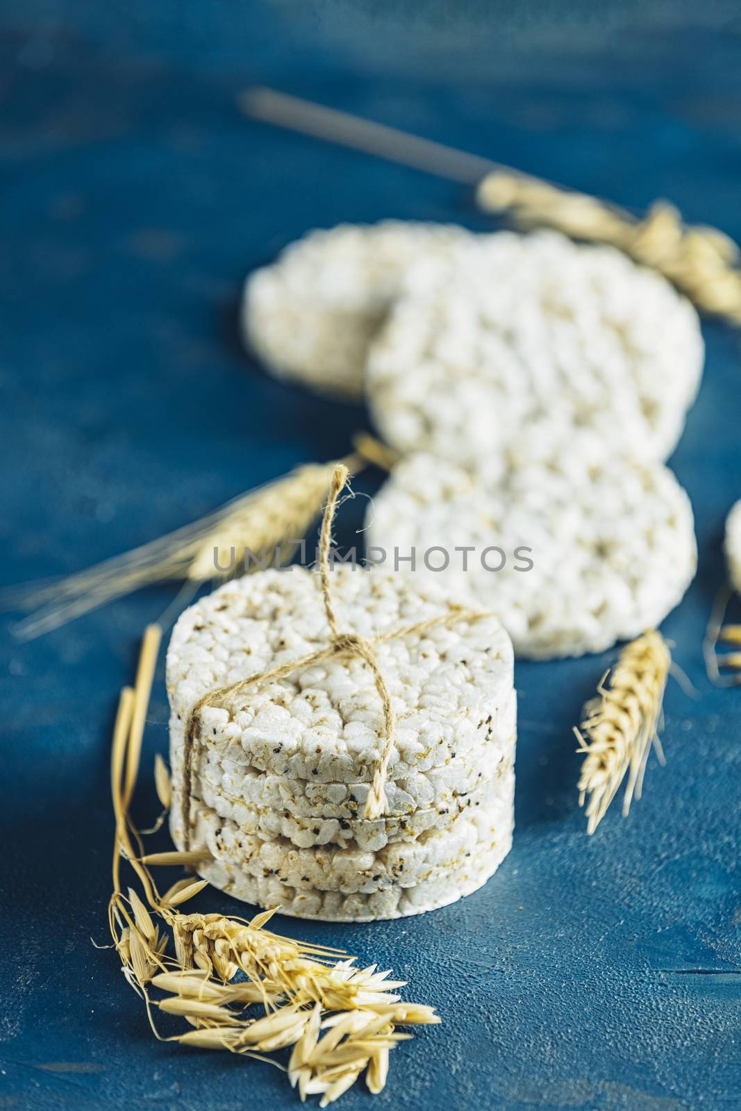 Stack of rice cakes. American puffed rice cakes. Healthy snacks with ears of wheat on classic blue concrete surface. Close up.