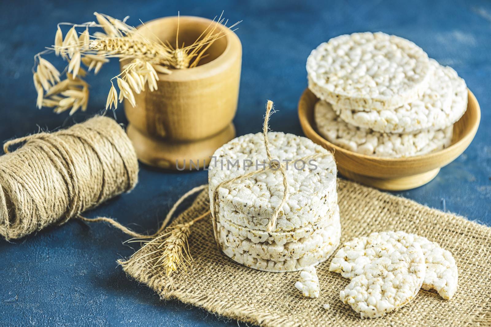 Stack of rice cakes. American puffed rice cakes. Healthy snacks with ears of wheat on classic blue concrete surface. Close up.