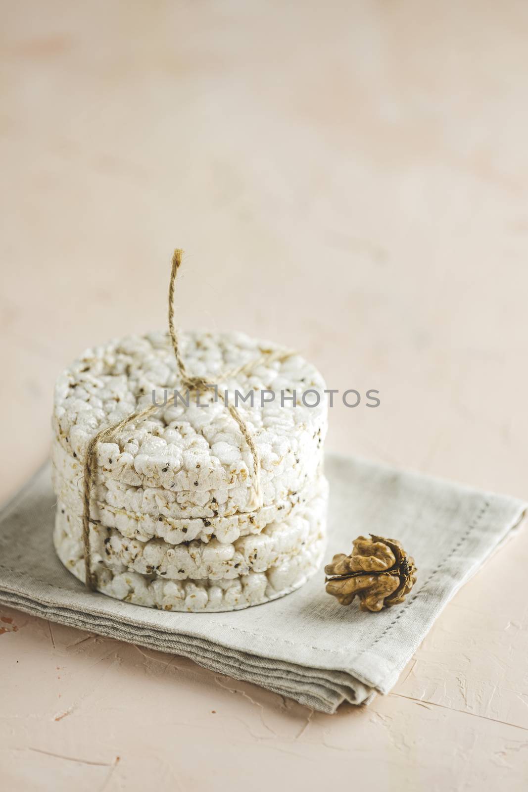 Stack of rice cakes. American puffed rice cakes. Healthy snacks with walnut on light pink concrete surface. Close up.	