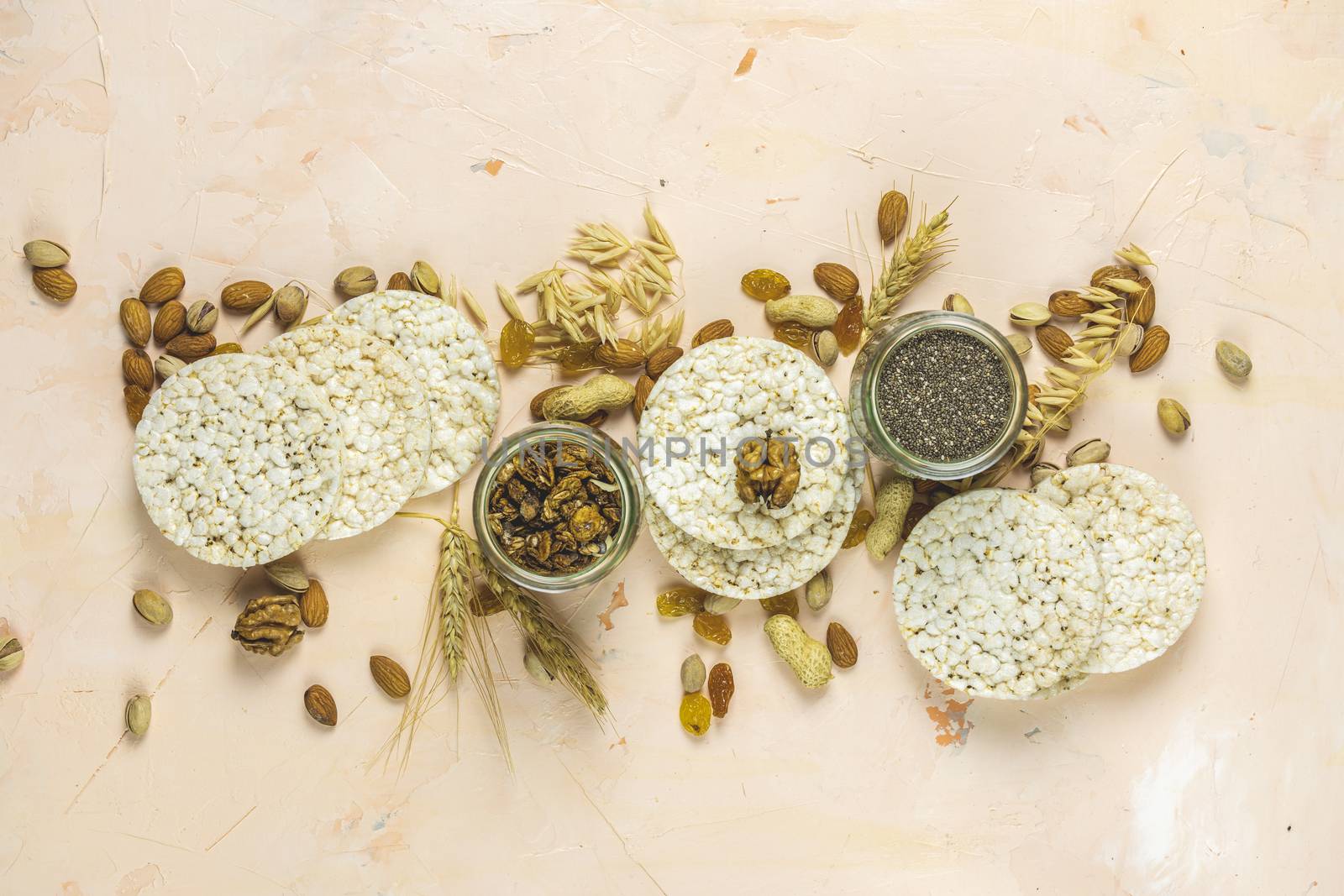 American puffed rice cakes. Healthy snacks with ears of wheat on light pink concrete surface, top view, flat lay, copy space for you text.