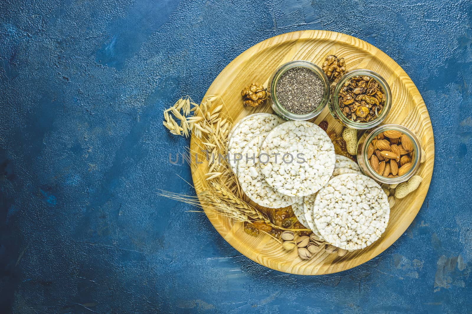 American puffed rice cakes. Healthy snacks with ears of wheat on classic blue concrete surface, top view, flat lay, copy space for you text. Color of 2020 year. Classic Blue, food trendy background.v