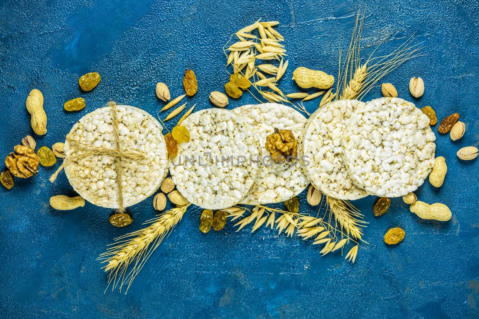 American puffed rice cakes. Healthy snacks with ears of wheat on classic blue concrete surface, top view, flat lay, copy space for you text. Color of 2020 year. Classic Blue, food trendy background.