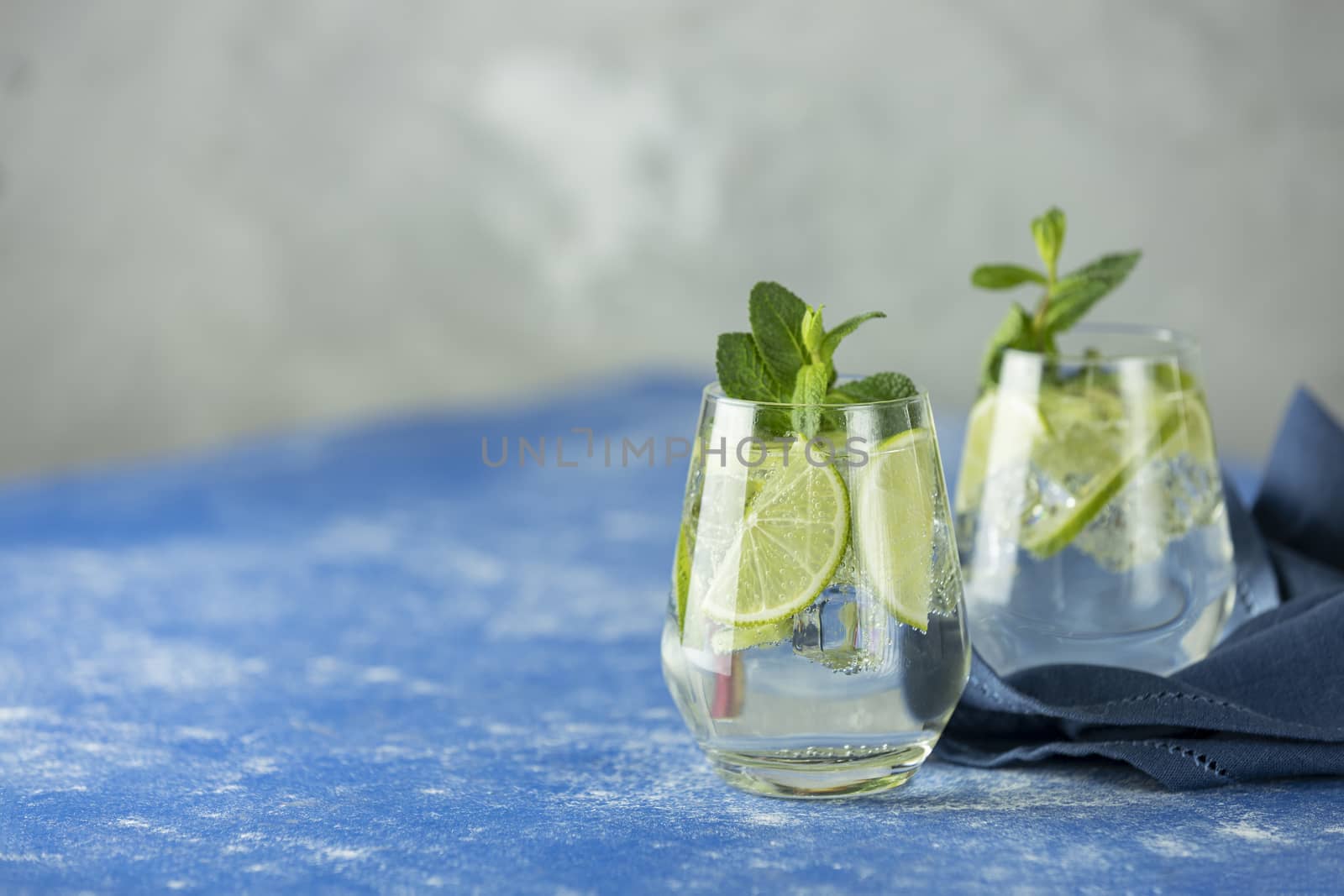 Two detox water or martini tonic cocktail with kiwi, lime, ice and mint. A new kind of mojito with kiwi, lime and mint and of course ice.	