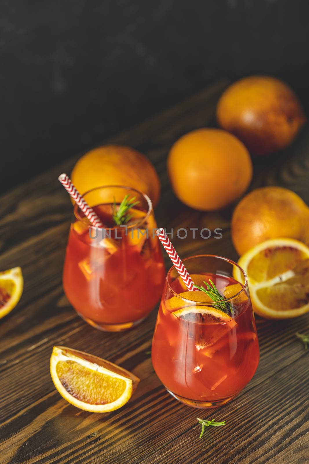 Milano spritzer alcoholic cocktail with red bitter, dry white wine, soda, red orange and ice. Dark wooden background, selective focus