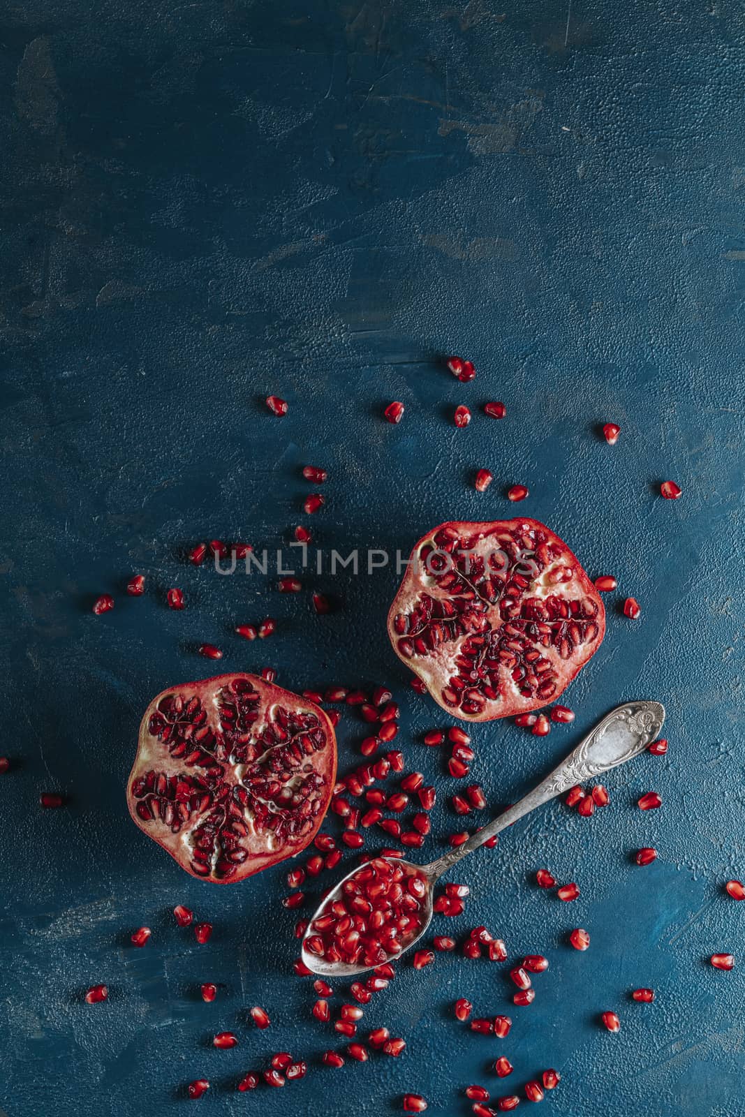 Fresh juicy pomegranate - whole and cut on a dark blue vintage background, top view, horizontal, with copy space