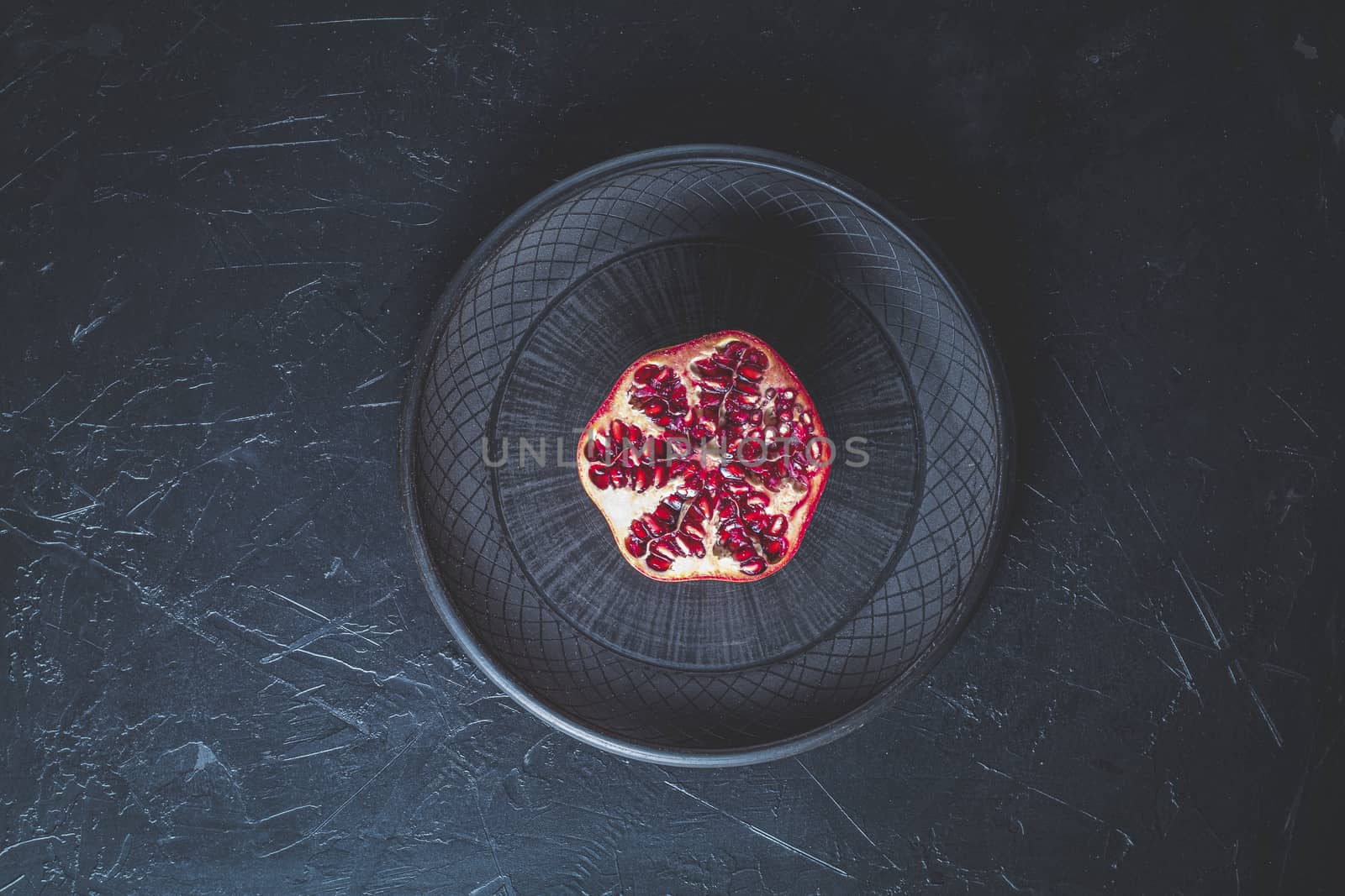 Fresh juicy pomegranate - whole and cut on a black vintage background, top view, horizontal, with copy space	