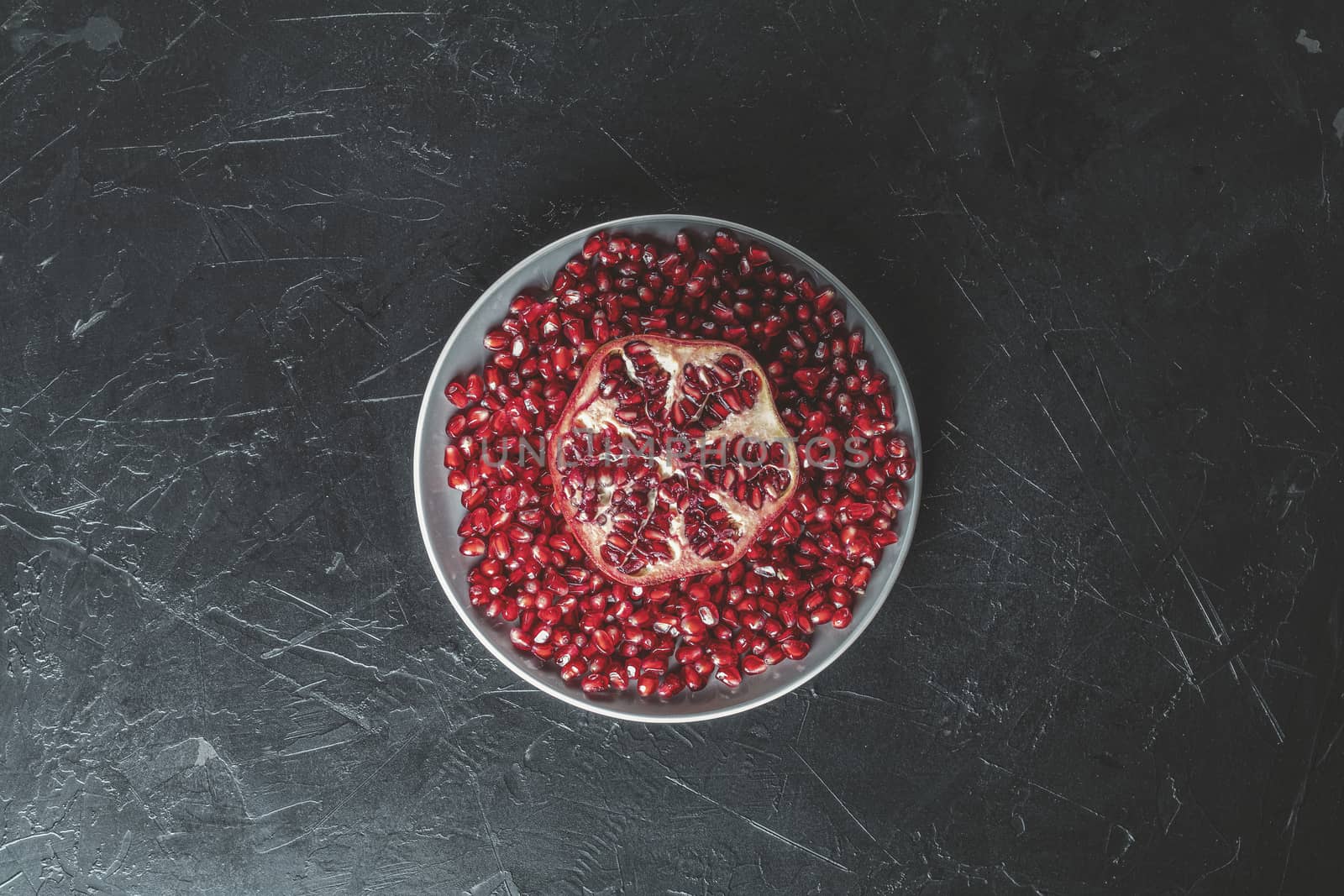 Fresh juicy pomegranate - whole and cut on a black vintage background, top view, horizontal, with copy space	