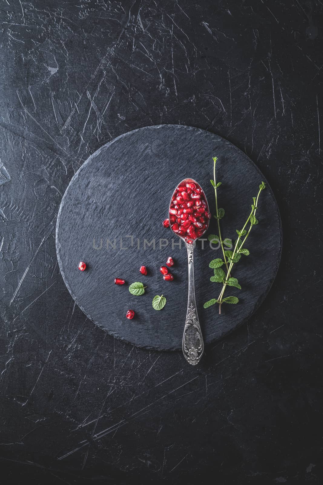 Fresh juicy pomegranate - whole and cut on a black vintage background, top view, horizontal, with copy space