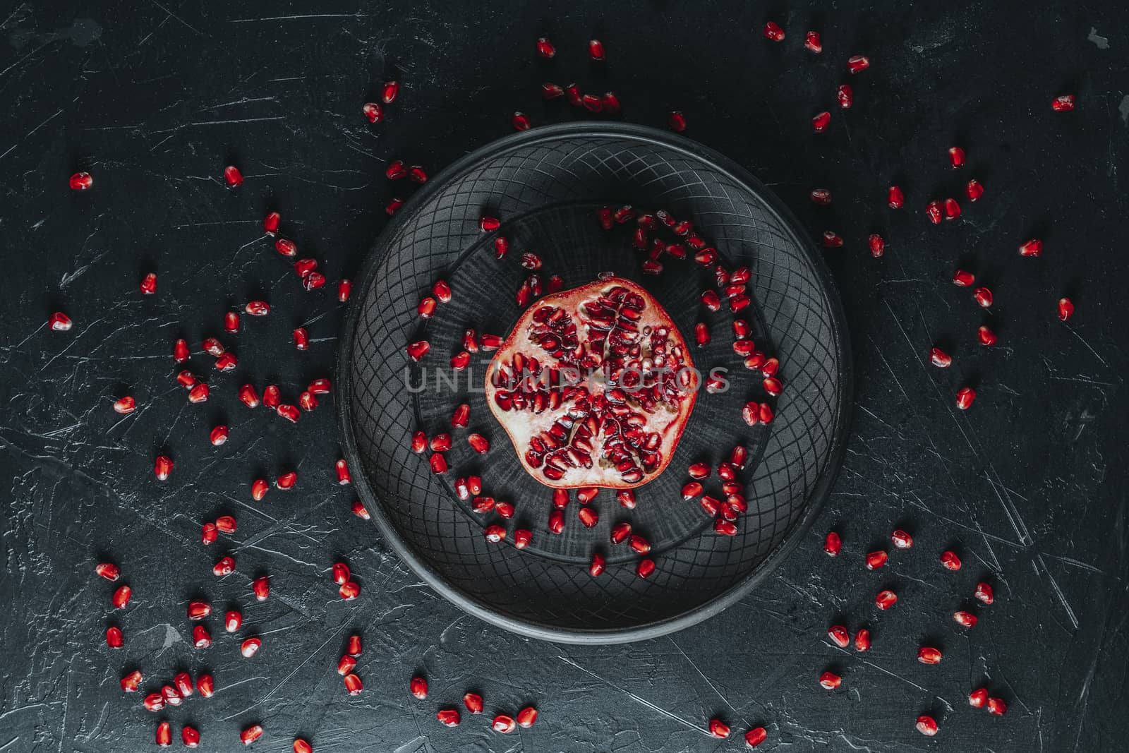 Fresh juicy pomegranate - whole and cut on a black vintage background, top view, horizontal, with copy space